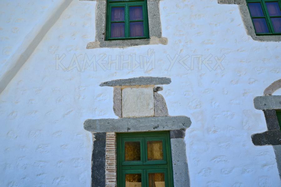 Каменная стена дома с деревянными окнами